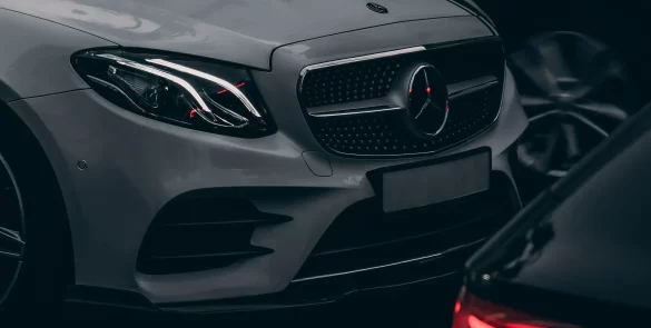 Sudrabains Mercedes-Benz automobilis starp citām automašīnām tumšā autostāvvietā